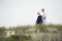 Happy senior couple walking on path on coast — Stock Photo