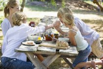 Happy mother and kids having food on summer backyard — Stock Photo