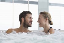 Retrato de pareja sonriente relajada descansando en bañera de hidromasaje - foto de stock