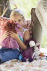 Созерцательная маленькая девочка держит игрушки в домике на дереве — стоковое фото