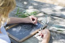 Menino fazendo desenho de folhas na ardósia ao ar livre — Fotografia de Stock