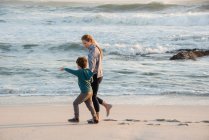 Счастливые мать и сын гуляют по пляжу — стоковое фото