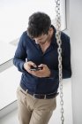 Young man using smartphone in light apartment — Stock Photo