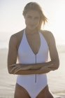 Portrait de jeune femme souriante en maillot de bain debout sur la plage — Photo de stock