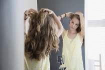 Ragazza adolescente esaminando i capelli nello specchio — Foto stock