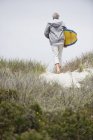 Rückansicht eines älteren Mannes mit Surfbrett am Strand — Stockfoto