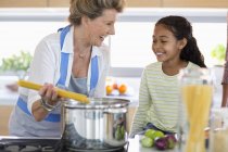 Happy senior woman with granddaughter preparing food in kitchen — Stock Photo
