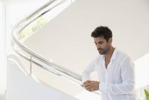 Вдумчивый человек стоит на лестнице в современном доме — стоковое фото