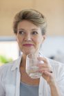 Happy senior woman holding glass of water — Stock Photo