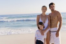 Portrait of relaxed family standing on sandy beach — Stock Photo