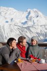 Пара и дочь едят на балконе горнолыжного курорта — стоковое фото