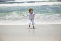 Усміхнений хлопчик грає на піщаному пляжі — стокове фото