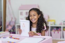 Happy little girl showing drawing at pink table — Stock Photo