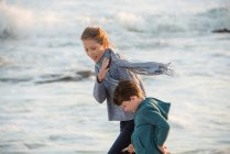 Happy mother and son walking on the beach — Stock Photo