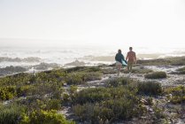 Entspanntes Paar spaziert an Küste mit Vegetation — Stockfoto