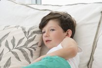 Happy little boy lying on bed and looking away — Stock Photo