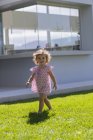 Милая малышка гуляет по зеленой лужайке летом на открытом воздухе — стоковое фото