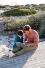 Father and son using a laptop on boardwalk — Stock Photo