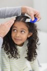 Мати використовує вошей гребінець на дочірньому волоссі — стокове фото