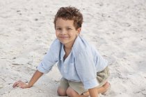 Portrait of smiling little boy playing in sand on beach — Stock Photo