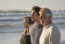 Heureuse famille réfléchie debout sur la plage ensemble et regardant la vue — Photo de stock