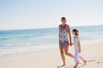 Жінка ходить на пляжі зі своєю дочкою — стокове фото