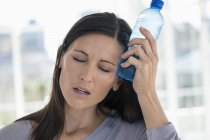 Woman holding water bottle on forehead — Stock Photo