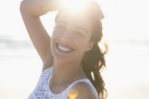 Portrait of smiling young woman on beach in sunlight — Stock Photo