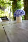 Flower pot on table in summer garden — Stock Photo