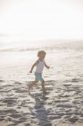 Petit garçon courant sur la plage de sable fin au soleil — Photo de stock