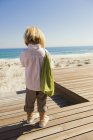 Девочка, стоящая на набережной на берегу моря — стоковое фото