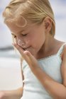 Little girl applying sunscreen lotion on face on beach — Stock Photo