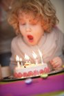 Ragazzo che spegne candele sulla torta di compleanno — Foto stock