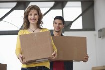 Couple carrying cardboard boxes and smiling — Stock Photo