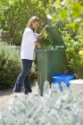 Женщина ищет утилизацию мусорных баков на открытом воздухе — стоковое фото