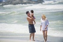 Coppia che cammina sulla spiaggia con figlioletta — Foto stock