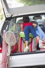 Visão traseira da menina de pé na bota do carro com sacos para viajar — Fotografia de Stock