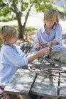Jungen basteln Rahmen aus Treibholz im Sommergarten — Stockfoto