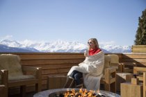 Woman sitting near fire pit on terrace of hotel, Crans-Montana, Swiss Alps, Switzerland — Stock Photo