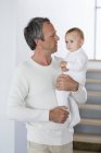 Feliz padre sosteniendo lindo bebé hija en casa - foto de stock
