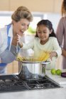 Seniorin mit Enkelin bereitet Essen in Küche zu — Stockfoto