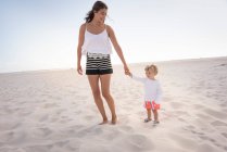 Happy mother with her little son walking on beach — Stock Photo