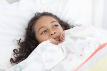 Dreamy little girl lying on bed — Stock Photo