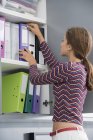 Молода бізнес-леді шукає файл в офісі — стокове фото