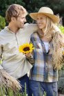 Young couple standing in scarecrow pose in field — Stock Photo