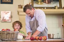 Cute little boy and his father kneading dough at kitchen — Stock Photo