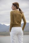 Rückansicht einer jungen Frau, die am Ufer des Sees steht und auf die Aussicht schaut — Stockfoto