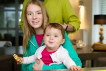 Retrato de dos niñas con su padre en casa - foto de stock