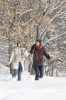 Jovem casal snowshoeing na floresta de inverno — Fotografia de Stock