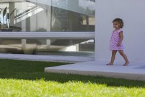 Cute baby girl walking on ledge in summer outdoors — Stock Photo